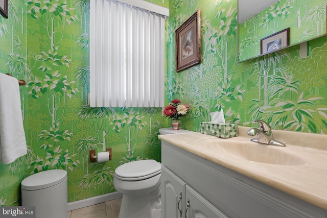 half bathroom featuring toilet, wallpapered walls, and vanity