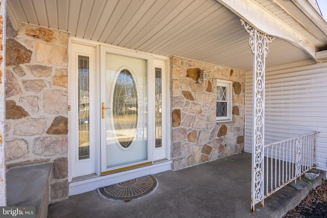 entrance to property featuring stone siding and covered porch