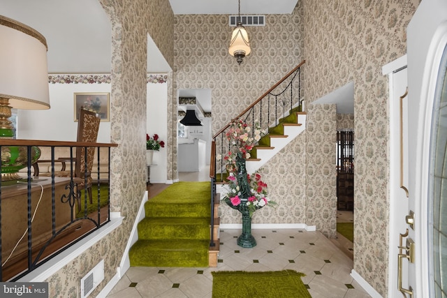 entryway featuring wallpapered walls, baseboards, stairway, and visible vents