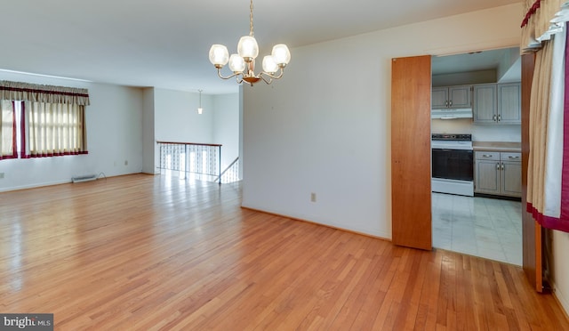 interior space with a chandelier, baseboards, visible vents, and light wood-style floors