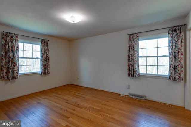 unfurnished room with light wood-type flooring, plenty of natural light, visible vents, and baseboards