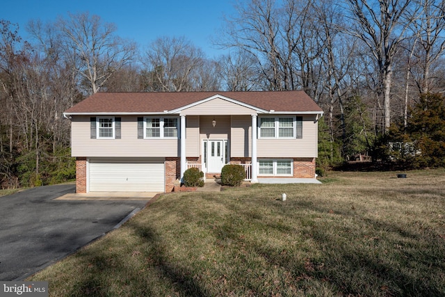 raised ranch with aphalt driveway, brick siding, an attached garage, and a front lawn