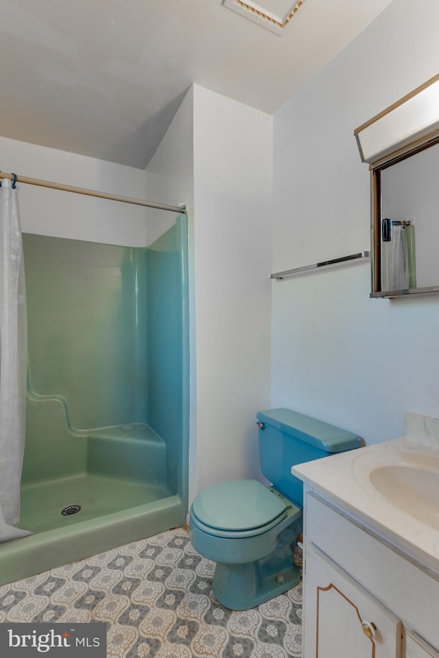 bathroom with toilet, tile patterned flooring, a shower stall, and vanity