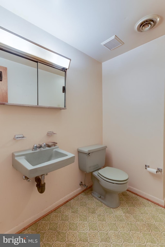 bathroom with visible vents, a sink, toilet, and baseboards