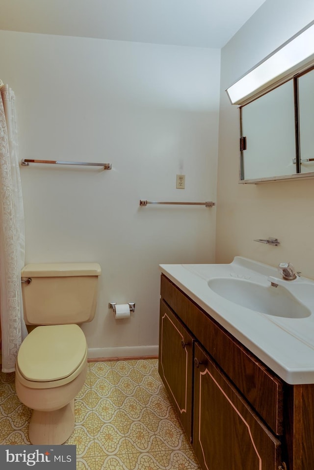 bathroom with baseboards, vanity, toilet, and tile patterned floors