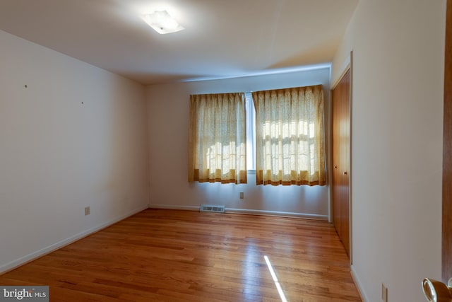 unfurnished room featuring light wood-style flooring, visible vents, and baseboards