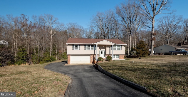 bi-level home with aphalt driveway, a front yard, brick siding, and an attached garage