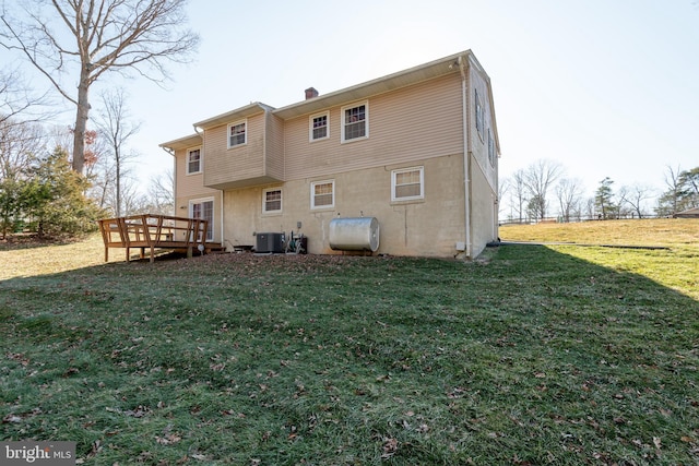 rear view of property with a deck, central AC, a lawn, heating fuel, and a chimney