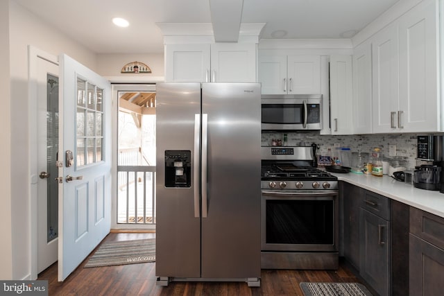 kitchen featuring stainless steel appliances, dark wood-style flooring, white cabinetry, light countertops, and tasteful backsplash