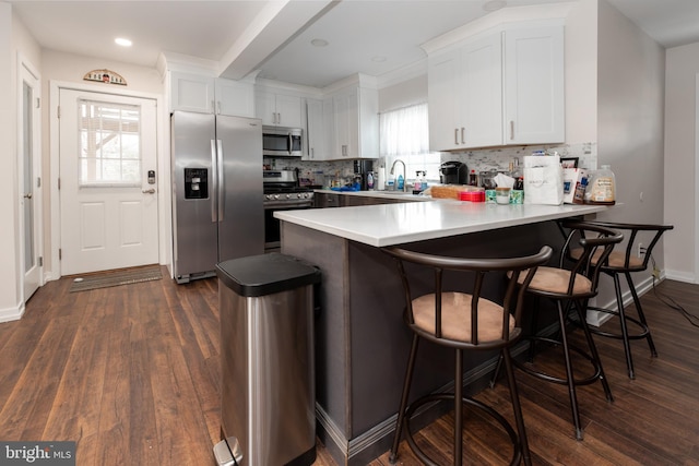 kitchen featuring stainless steel appliances, dark wood-style flooring, a peninsula, and a sink