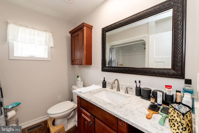 bathroom with toilet, vanity, visible vents, and baseboards