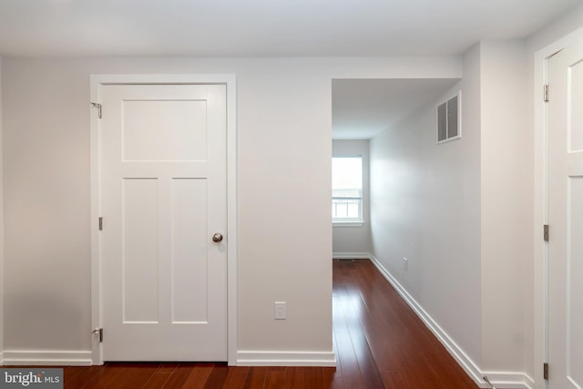 hall featuring dark wood-style floors, baseboards, and visible vents