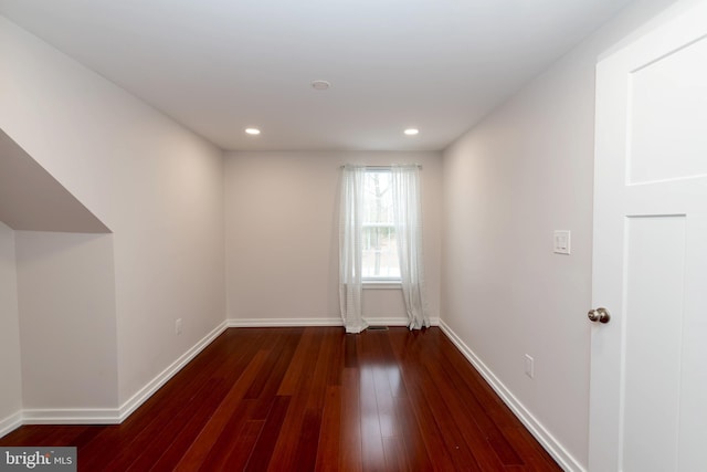 spare room featuring recessed lighting, wood-type flooring, and baseboards