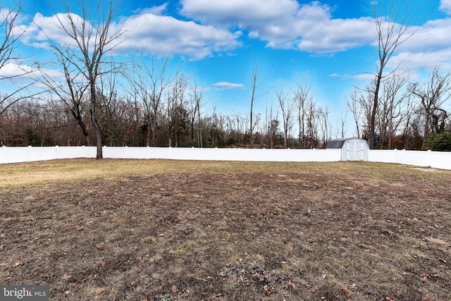 view of yard with an outbuilding, a fenced backyard, and a storage unit