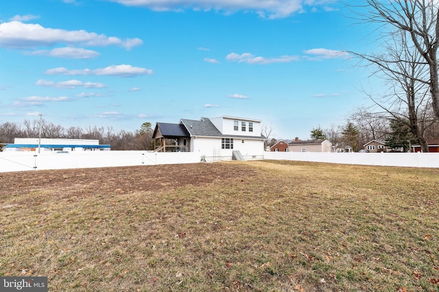 rear view of property featuring a fenced backyard and a yard