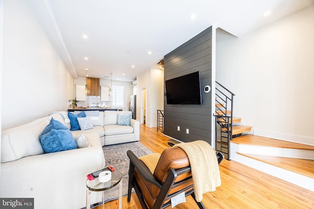 living area featuring stairs, light wood finished floors, baseboards, and recessed lighting