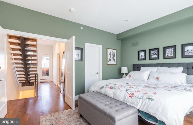 bedroom with wood finished floors, visible vents, and baseboards