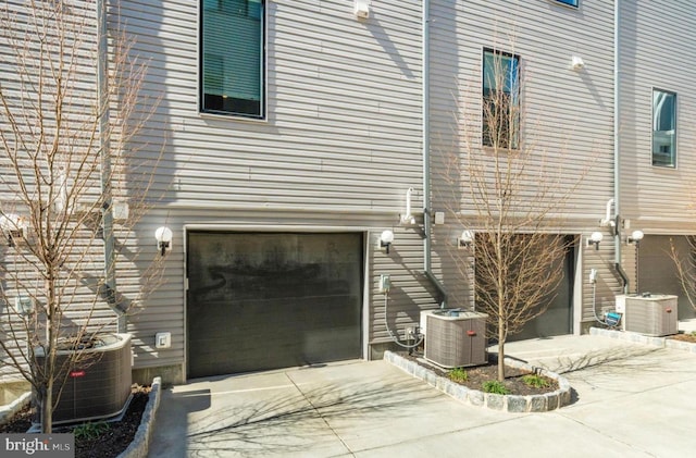 view of side of home with driveway, a garage, and central AC