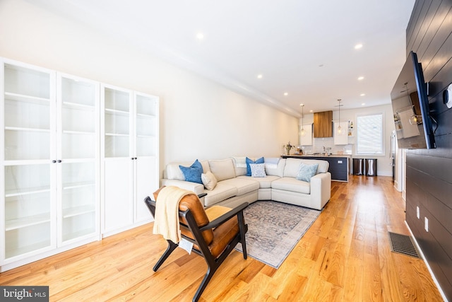 living area with light wood-type flooring, visible vents, and recessed lighting