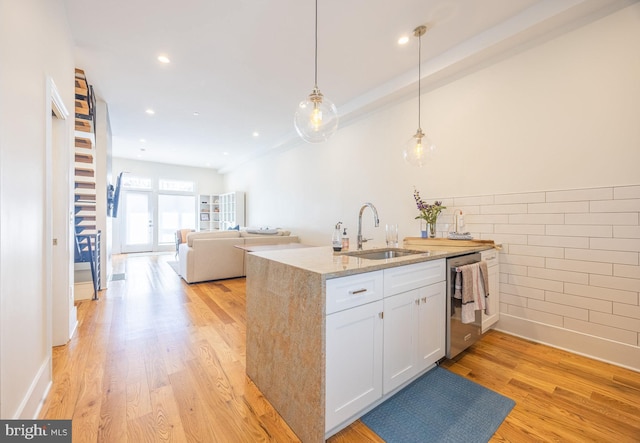 kitchen with white cabinetry, a sink, light wood-style flooring, and stainless steel dishwasher