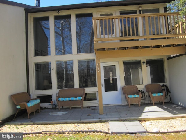 back of property with a balcony, a patio area, and stucco siding