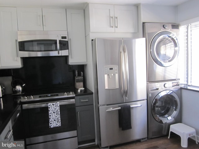 kitchen with appliances with stainless steel finishes, stacked washing maching and dryer, white cabinetry, and tasteful backsplash