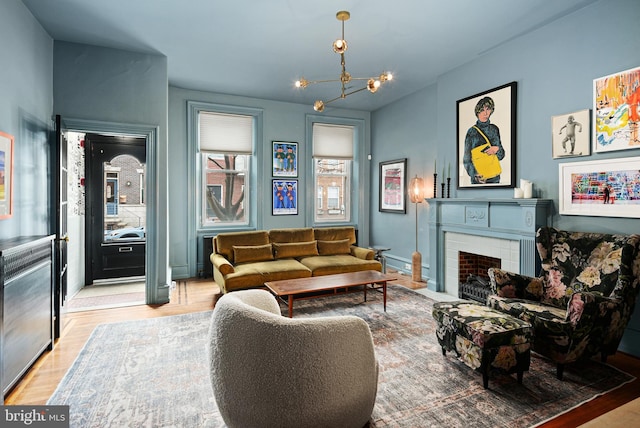 living area with a fireplace, a chandelier, and wood finished floors