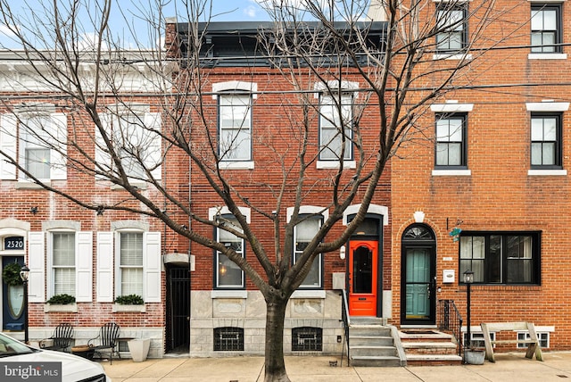 townhome / multi-family property featuring entry steps, stone siding, and brick siding