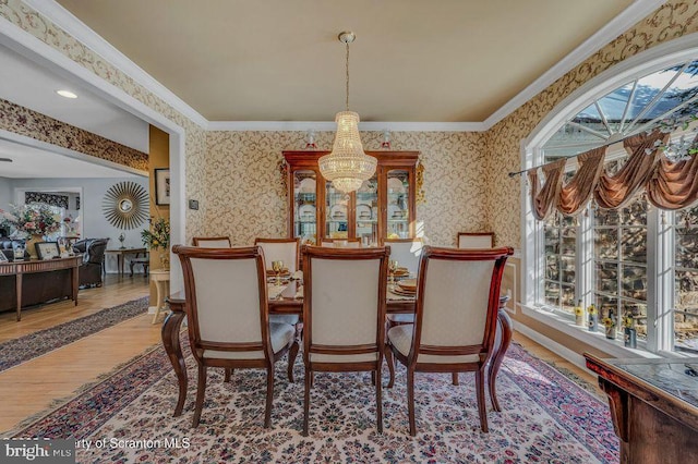 dining space with ornamental molding, wood finished floors, a wealth of natural light, and wallpapered walls