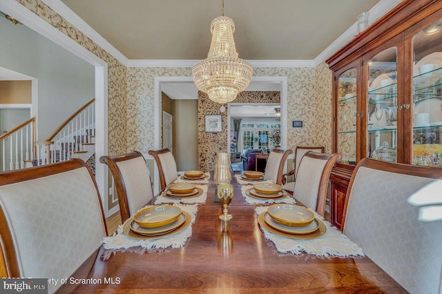 dining space with crown molding, stairway, an inviting chandelier, and wallpapered walls