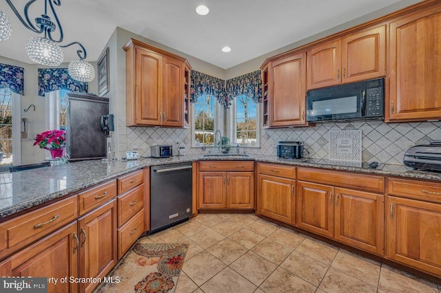 kitchen featuring light tile patterned floors, stone counters, a sink, brown cabinets, and black appliances