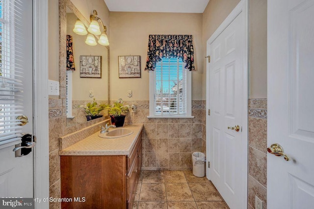 bathroom with tile patterned flooring, a wainscoted wall, tile walls, and vanity