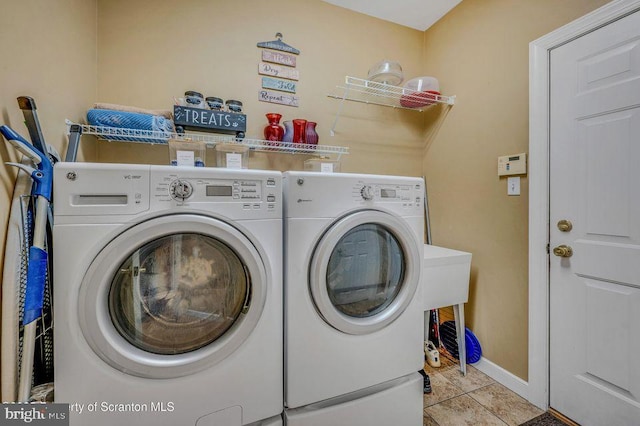 laundry room with laundry area, baseboards, washing machine and clothes dryer, and light tile patterned floors