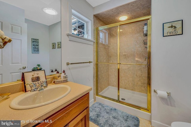 full bath with a stall shower, baseboards, and vanity