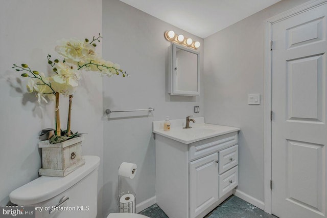 bathroom featuring baseboards, vanity, and toilet