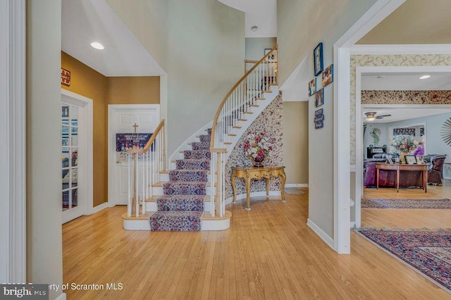 interior space featuring stairway, a high ceiling, ornamental molding, wood finished floors, and baseboards