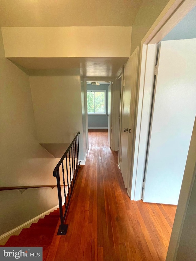 corridor with baseboards and wood finished floors