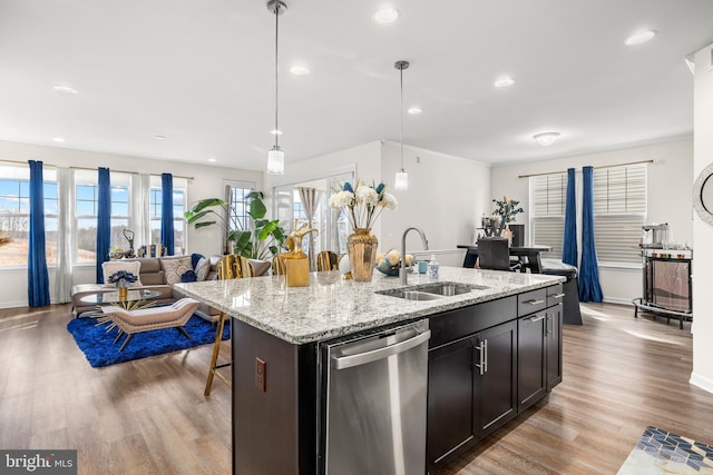 kitchen with dishwasher, an island with sink, a sink, and light wood-style floors