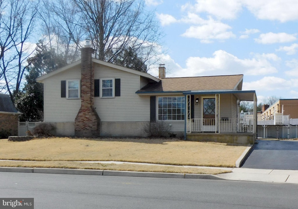 tri-level home featuring a chimney, fence, and a porch