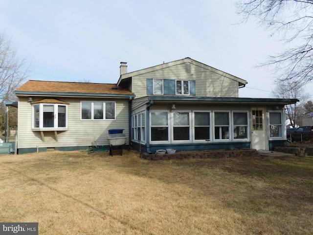 back of house featuring a yard, a chimney, and a sunroom