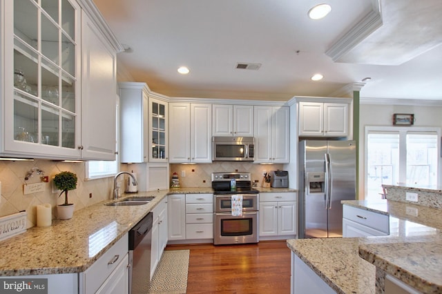 kitchen with visible vents, ornamental molding, stainless steel appliances, white cabinetry, and a sink