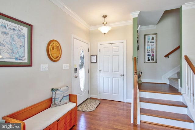 entryway featuring baseboards, wood finished floors, stairs, and ornamental molding