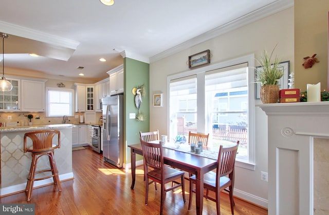 dining room with recessed lighting, crown molding, baseboards, and wood finished floors