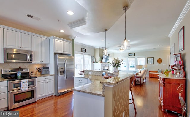 kitchen with crown molding, wood finished floors, visible vents, and appliances with stainless steel finishes