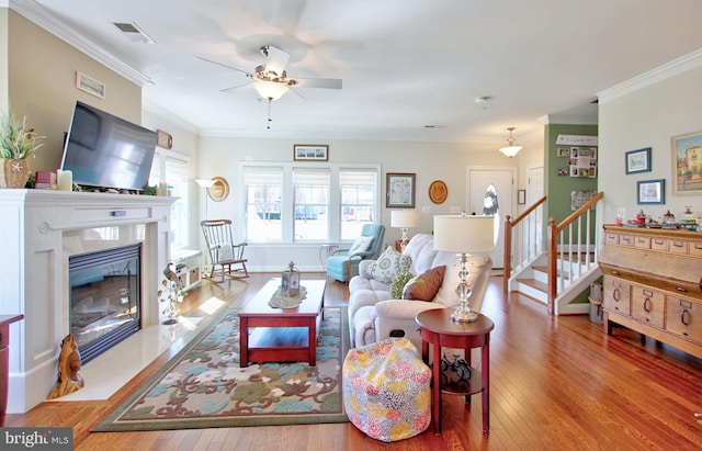 living area with visible vents, a fireplace, stairs, and hardwood / wood-style flooring