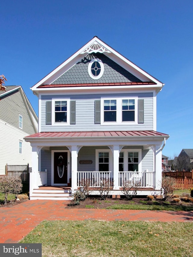 view of front facade with a standing seam roof, fence, and covered porch