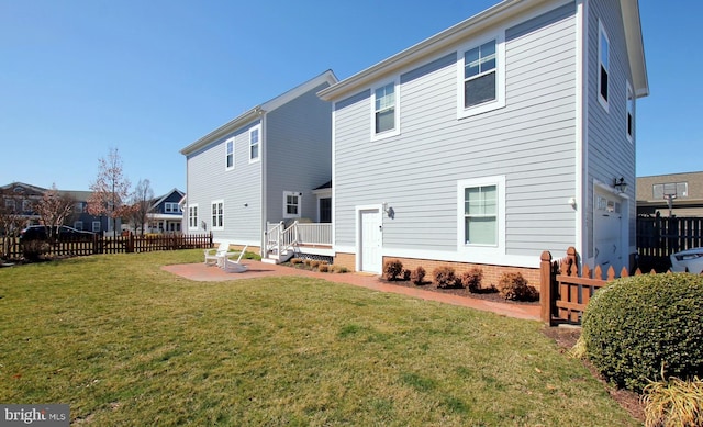 rear view of property with a patio, a lawn, and fence