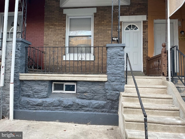 property entrance with covered porch and brick siding