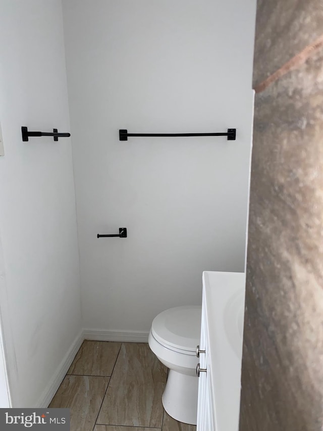 bathroom featuring vanity, toilet, and baseboards