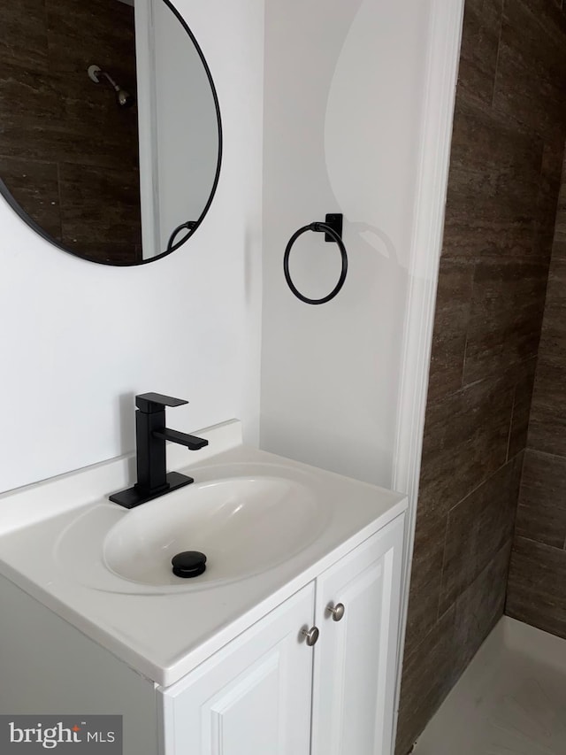 bathroom with a tile shower and vanity